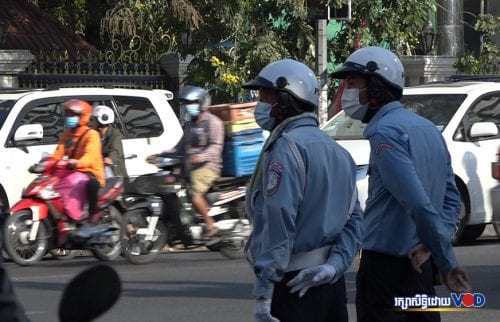 ​ប៉ូលិសចរាចរណ៍​ពីរ​នាក់​ឈរ​ចាំ​សម្រួល​ចរាចរណ៍​ដល់​ពលរដ្ឋ​ធ្វើដំណើរ​នៅ​ម្ដុំ​ស្ដា​តអូឡាំពិក ថ្ងៃទី១៤ ខែមករា ឆ្នាំ២០២១។