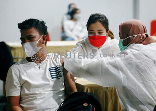 បុរសម្នាក់ទទួលថ្នាំបង្ការប្រឆាំងនឹងជំងឺឆ្លងកូវីដ-១៩ ក្នុងអំឡុងពេលដំណើរការកម្មវិធីចាក់ថ្នាំដល់អ្នកដំណើរនៅអាកាសយានដ្ឋានអន្តរជាតិ Soekarno-Hatta ក្នុងទីក្រុង Tangerang ប្រទេសឥណ្ឌូនេស៊ី ថ្ងៃទី៦ ខែកក្កដា ឆ្នាំ២០២១។ (REUTERS/Ajeng Dinar Ulfiana)