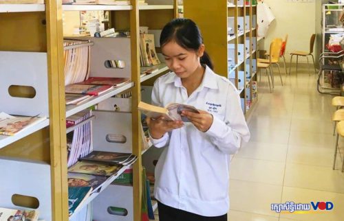 យុវតី ពុន ស៊ីថា ឈរអានសៀវភៅនៅក្នុងបណ្ណាល័យនៃវិទ្យាល័យសម្ដេចឪសម្ដេចម៉ែ ខេត្តរតនគិរី។