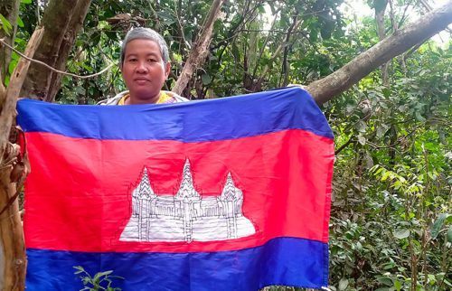សកម្មជនដីធ្លី អ្នកស្រី សាត ផា ឈរកាន់ទង់ជាតិខ្មែរ អំឡុងពេលធ្វើដំណើរភៀសខ្លួនទៅរកទីតាំងសុវត្ថិភាព ក្រោយអ្នកស្រីទទួលការគំរាមកំហែង។