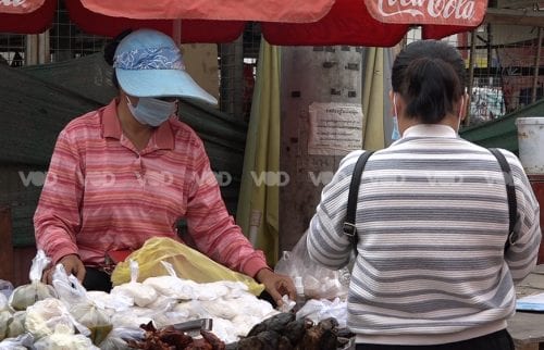 កម្មការិនីម្នាក់នៃរោងចក្រ វ៉ាយ&ដាប់បែលយូ (Y&W) ឈរទិញអាហារពីអ្នកលក់នៅផ្សារព្រែកជ្រៃ ស្ថិតនៅខណ្ឌដង្កោ រាជធានីភ្នំពេញ ថ្ងៃទី០៣ ខែមីនា ឆ្នាំ២០២១។ (ហ៊ី ឆាយ)