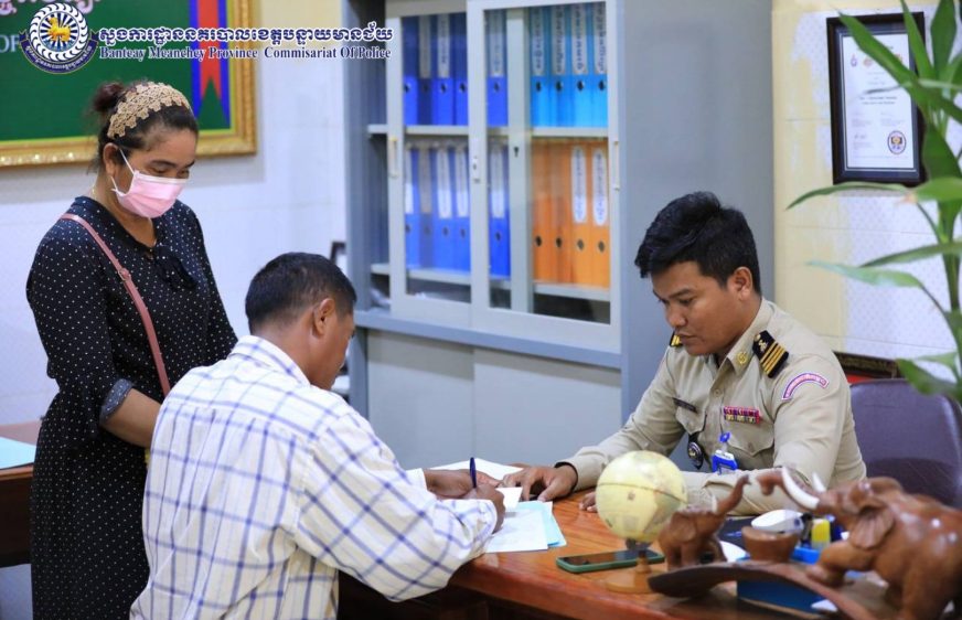 មន្ត្រីសាលាស្រុកស្វាយចេកម្នាក់ គឺលោក អឿន ធី(បែរខ្នង អាវក្រឡាការ៉ូ) ត្រូវបាននគរបាលនៃស្នងការដ្ឋាននគរបាលខេត្តបន្ទាយមានជ័យ កោះហៅសួរនាំ និងធ្វើកិច្ចសន្យាជុំវិញការបង្ហោះព័ត៌មានពាក់ព័ន្ធរឿងស្រូវចុះថោក និងជេប្រមាថអាជ្ញាធរ កាលពីថ្ងៃទី១៨ ខែវិច្ឆិកា ឆ្នាំ២០២២។ (ស្នងការដ្ឋាននគរបាលខេត្តបន្ទាយមានជ័យ)