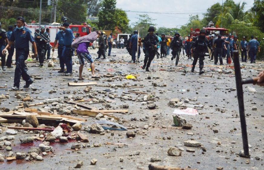 Philippine National Police clear the highway off of blood and debris following a violent protest along a national highway in Kidapawan city southern Philippines Friday April 1, 2016. Officials say at least two people have been killed and dozens wounded when gunfire erupted as police attempted to clear a 4-day-old protest by farmers, who have been demanding government financial aid in the wake of a seven-month drought in the province. A journalist at the site counted 13 injured protesters. (AP Photo/Williamor Magbanua)