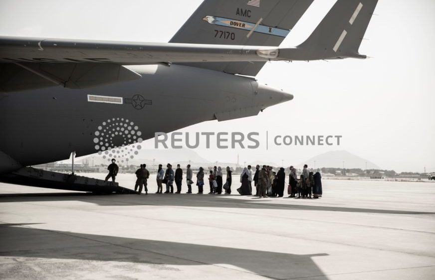 ពលរដ្ឋអាហ្វហ្គានីស្ថាន និងពលរដ្ឋជាជនបរទេសរស់នៅអាហ្វហ្គានីស្ថាន រង់ចាំឡើងយន្តហោះ Boeing C-17 Globemaster III អំឡុងពេលត្រៀមភៀសខ្លួនតាមអាកាសយានដ្ឋានអន្តរជាតិ ហាមីដ កាហ្សៃ (Hamid Karzai) ក្នុងទីក្រុងកាប៊ុល ប្រទេសអាហ្វហ្គានីស្ថាន ថ្ងៃទី៣០ ខែសីហា ឆ្នាំ២០២១។ (U.S. Marine Corps/Staff Sgt. Victor Mancillal/Handout via REUTERS)