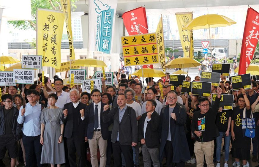 សកម្មជនគាំទ្រលទ្ធិប្រជាធិបតេយ្យឈរស្រែកនិងកាន់បដាតវ៉ាទាមទារសិទ្ធិ រង់ចាំតុលាការចេញសាលក្រមនៅ Occupy Central  នៅហុងកុង នាព្រឹកថ្ងៃទី០9 មេសា 2019។ រូបភាព៖ REUTERS / Tyrone Siu