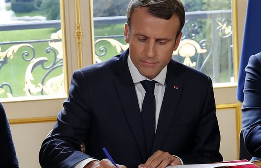 French President Emmanuel Macron signs documents in front of the media to promulgate a new labor bill in his office at the Elysee Palace in Paris, France, Friday, Sept. 22, 2017. Macron has signed Friday five decrees paving the way to the implementation of labor measures aimed at boosting growth, his first major reform since his election. (Philippe Wojazer/Pool Photo via AP)