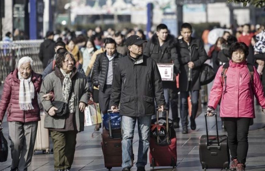 Travelers carrying luggage walk towards the entrance of the Shanghai Railway Station in Shanghai, China (Photographer: Qilai Shen/Bloomberg)